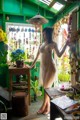 A woman standing in front of a green room filled with plants.