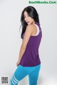 A woman in a purple tank top and blue leggings.